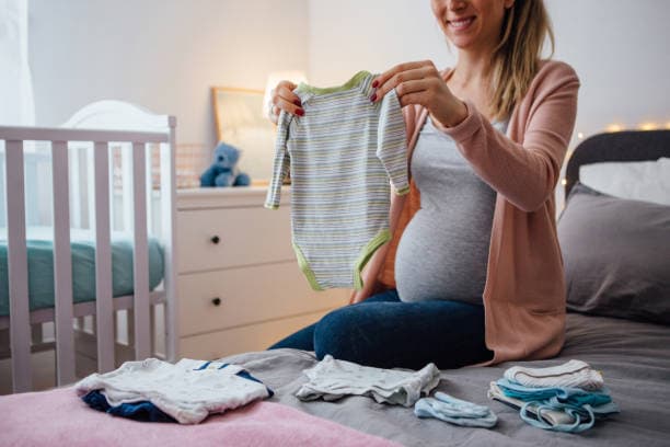 Hamile bir kadın bebek kıyafetleri hazırlarken – bebek alışverişi ve hazırlık süreci